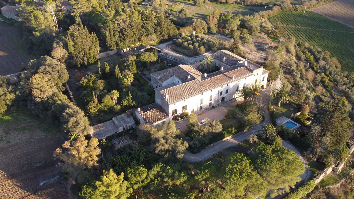Luftaufnahme einer herrschaftlichen Finca auf Mallorca im Abendlicht, umgeben von Gärten, Palmen und Feldern