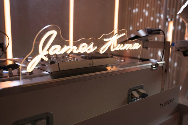 Leuchtender Neon-Schriftzug James Kuma auf der weißen DJ-Booth